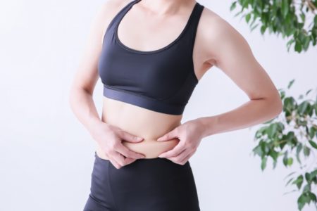 水分不足で太ってしまったとお腹を気にする女性の画像