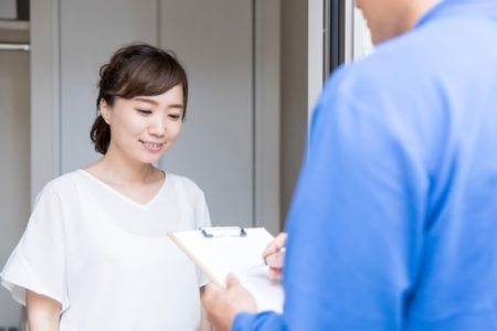 引越し業者とウォーターサーバーの移動を確認する女性の画像