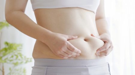お腹をつまむ女性の画像